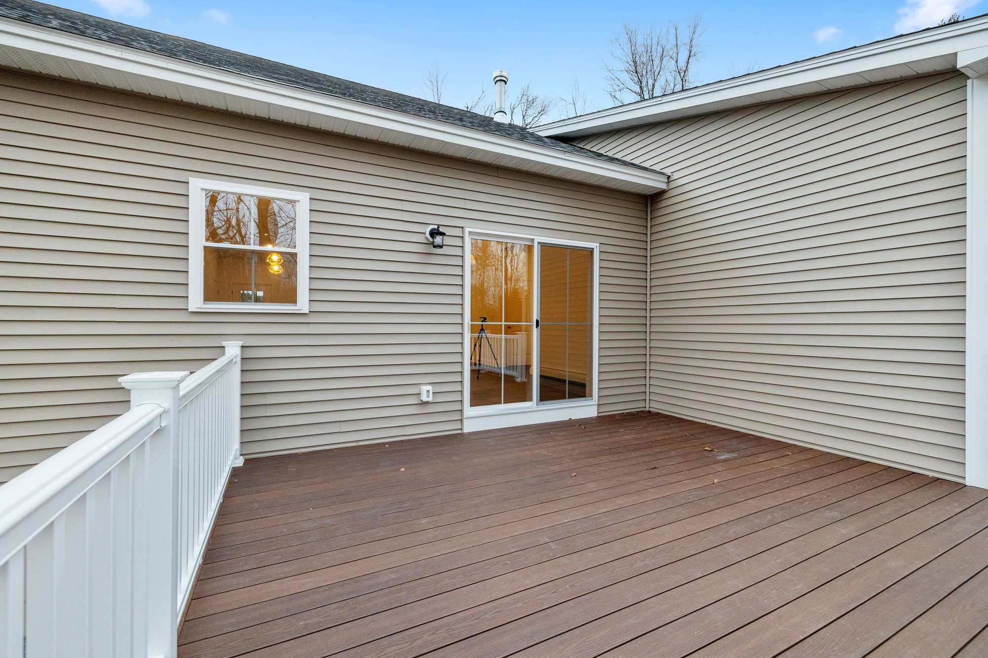 Composite deck with white railings and sliding door built by Five Oaks Roofing Plus