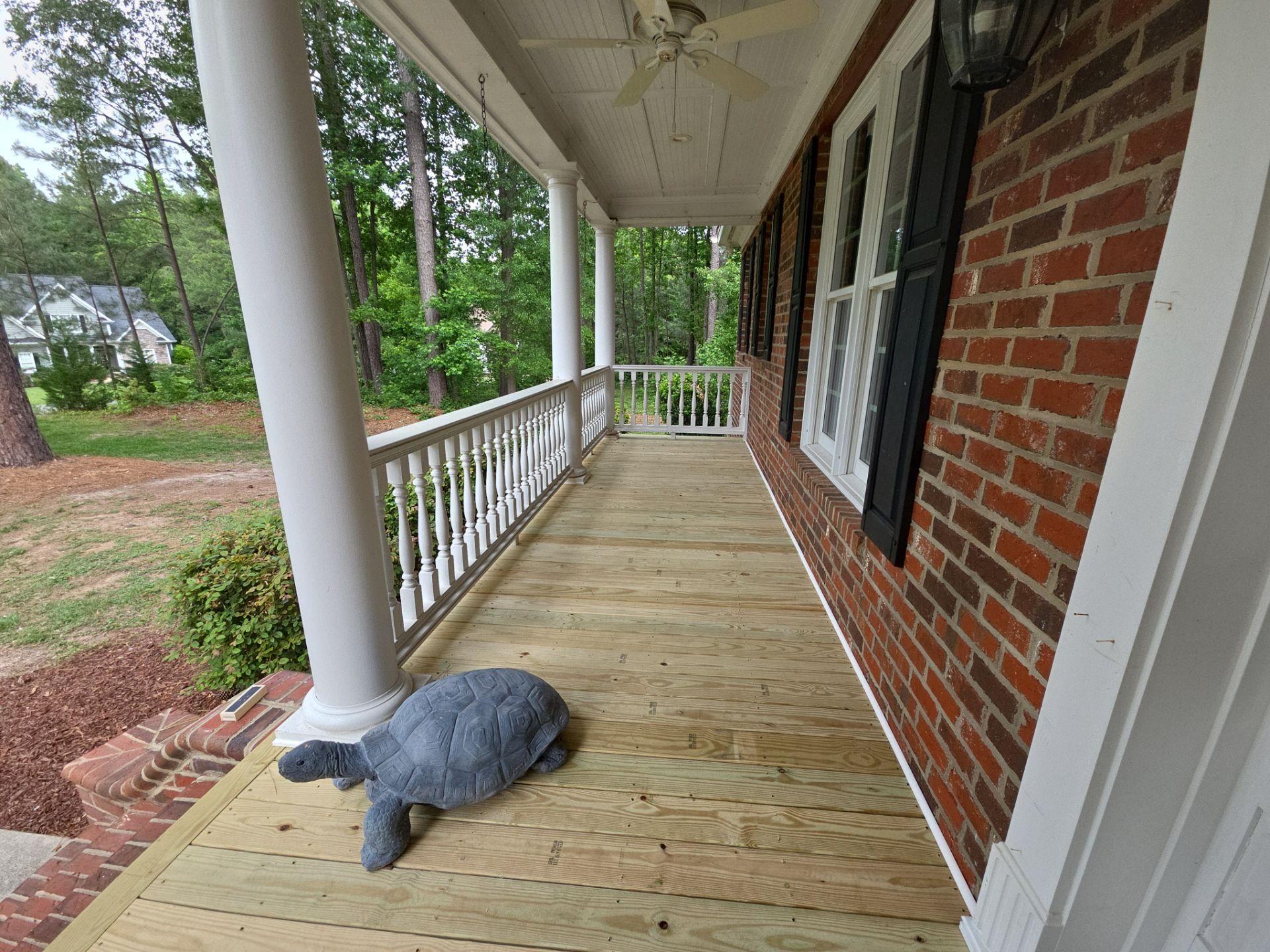 Wood porch deck with white railings built by Five Oaks Roofing Plus