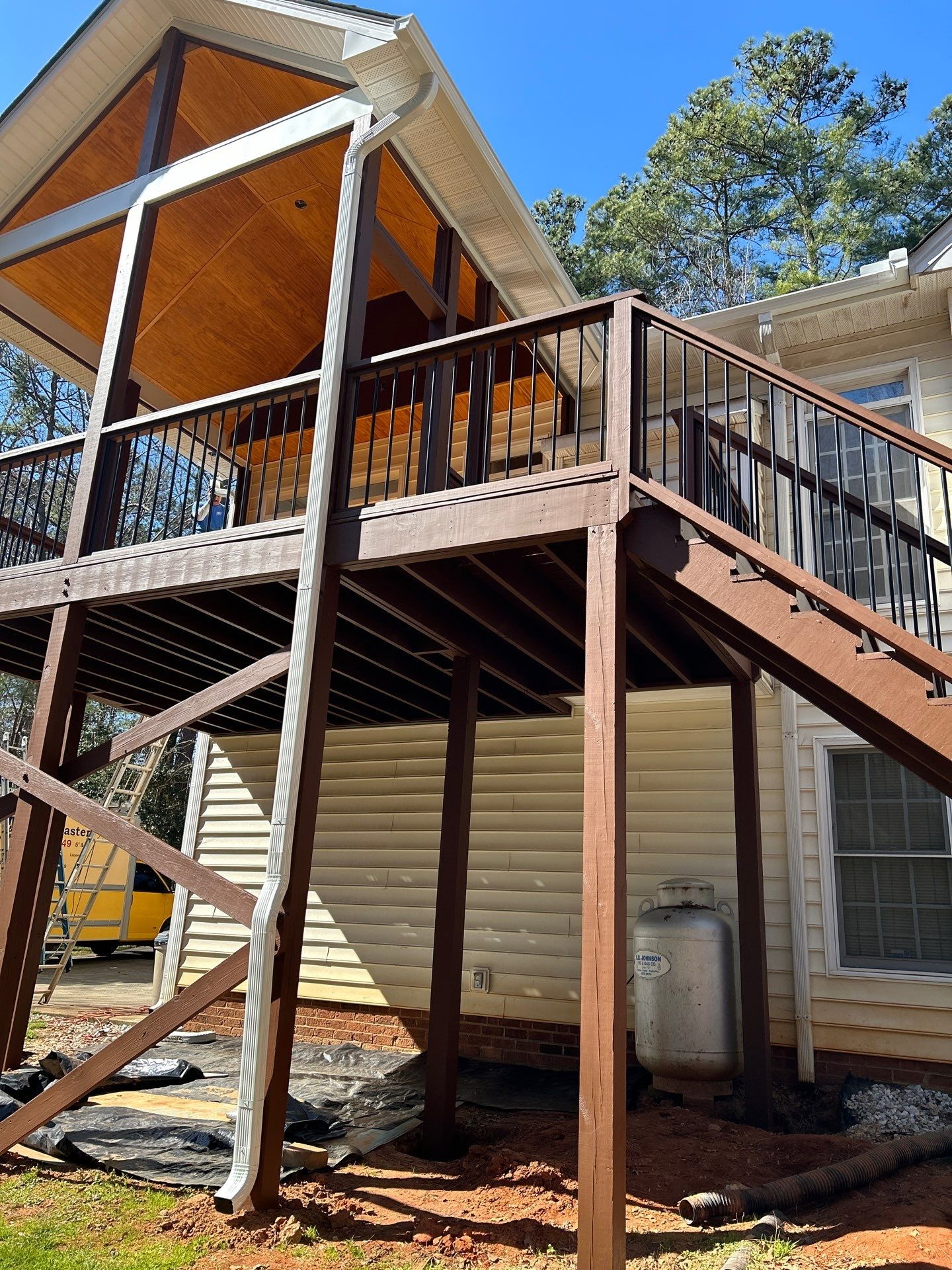 Two-story covered deck with black railings and stairs built by Five Oaks Roofing Plus